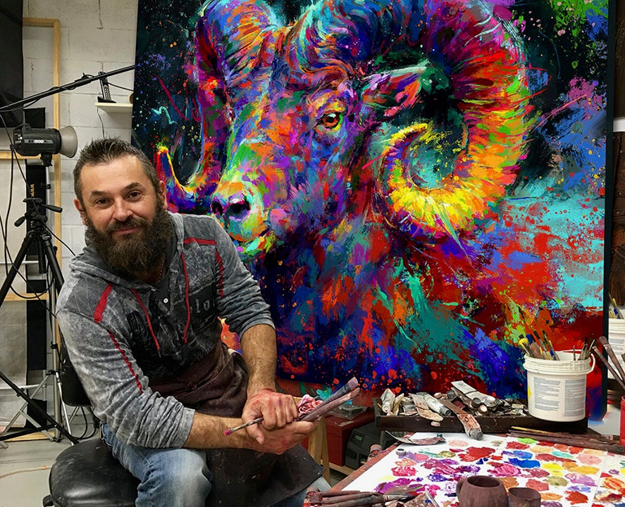 blend cota painting in his blended expressionism style, posing with his original oil painting of the ram spirit, blend cota studios art